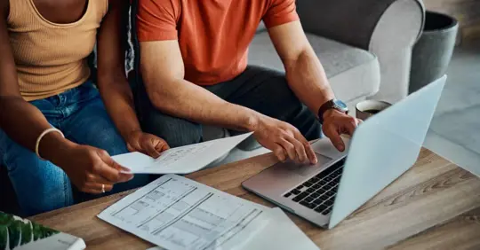 Couple using a laptop to check their joint debts