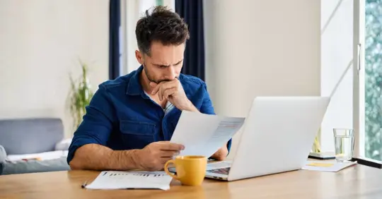 Sad man looking at financial documents at home